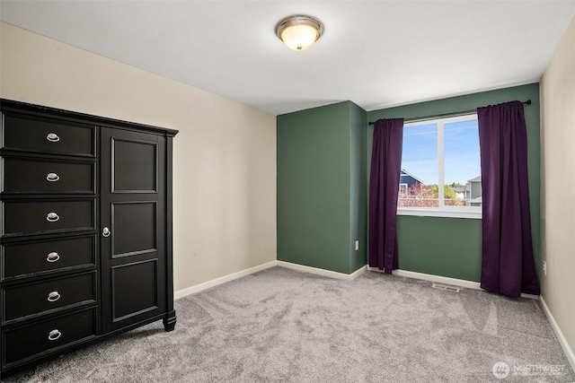 unfurnished bedroom featuring baseboards, visible vents, and carpet
