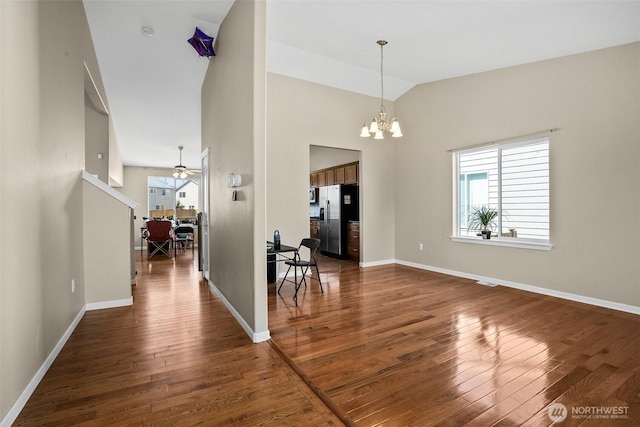 dining space with baseboards, ceiling fan with notable chandelier, lofted ceiling, and dark wood-type flooring