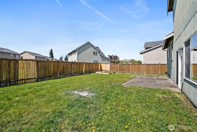 view of yard with a patio, a fenced backyard, and a residential view