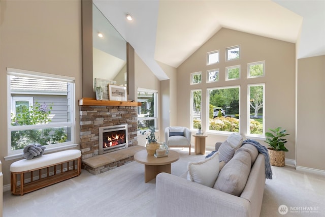 carpeted living room featuring a stone fireplace, baseboards, and lofted ceiling