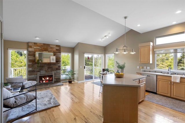 kitchen with stainless steel dishwasher, open floor plan, light brown cabinets, light countertops, and lofted ceiling
