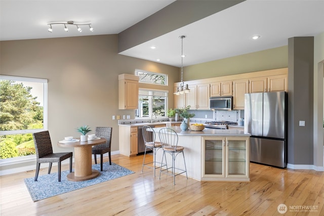 kitchen featuring appliances with stainless steel finishes, light countertops, light brown cabinets, a kitchen island, and light wood finished floors