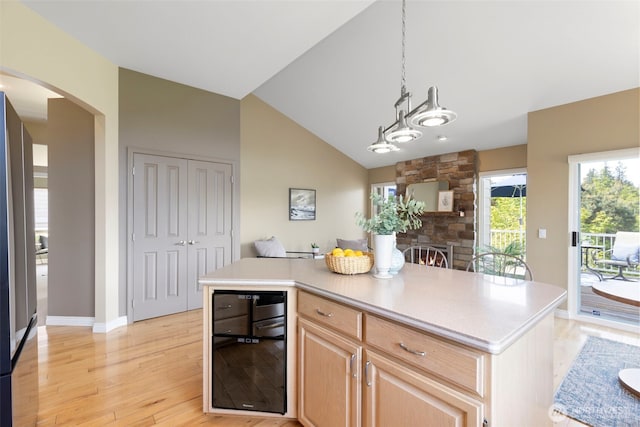 kitchen featuring beverage cooler, light brown cabinetry, arched walkways, light countertops, and light wood-style floors