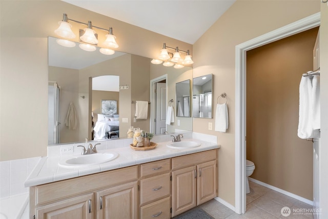ensuite bathroom featuring tile patterned floors, toilet, and double vanity