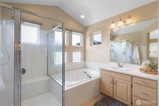 bathroom with vaulted ceiling, a shower stall, a tub with jets, vanity, and healthy amount of natural light