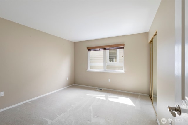 unfurnished room with baseboards and light colored carpet