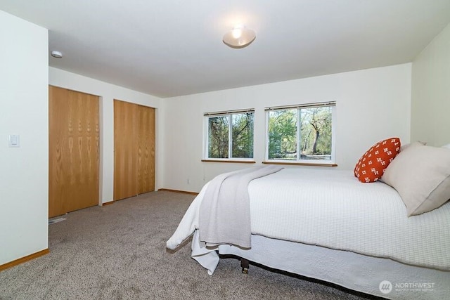 bedroom featuring multiple closets, carpet flooring, and baseboards