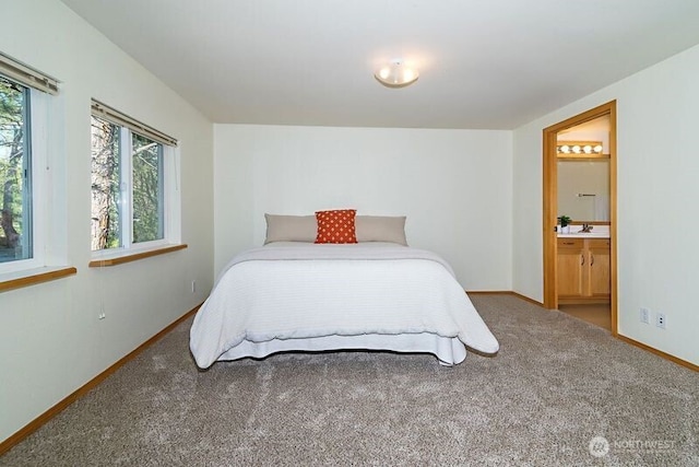 carpeted bedroom with connected bathroom and baseboards