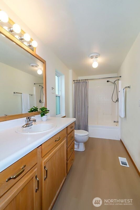bathroom featuring toilet, vanity, visible vents, and wood finished floors
