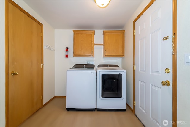 washroom featuring cabinet space, washing machine and clothes dryer, and baseboards