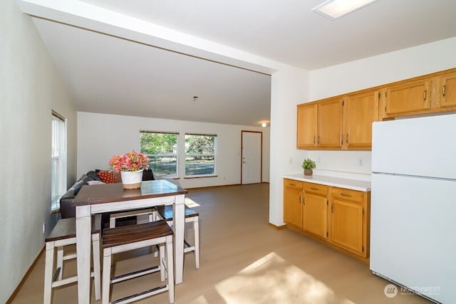 kitchen featuring lofted ceiling, light countertops, and freestanding refrigerator