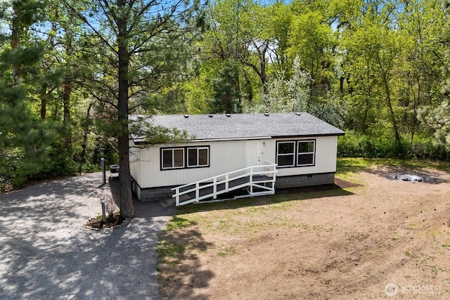 rear view of property featuring a shingled roof and crawl space