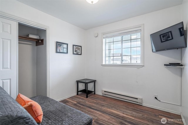 bedroom featuring baseboard heating, a closet, and dark wood finished floors