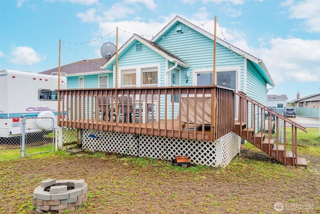 rear view of house with a wooden deck and fence