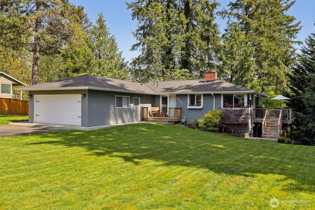rear view of house with a garage, a chimney, aphalt driveway, and a yard