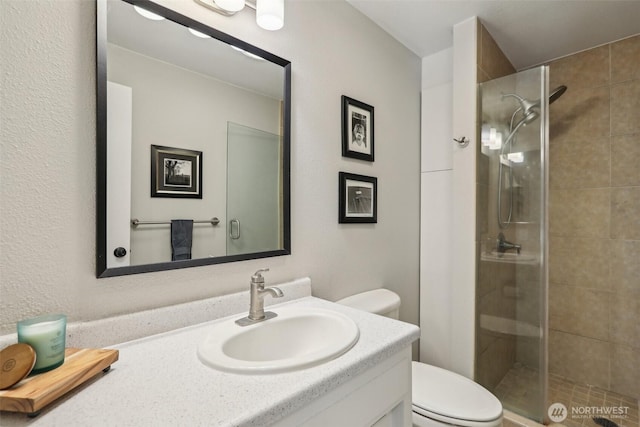 full bathroom with toilet, a stall shower, and vanity
