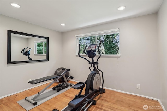 workout room featuring baseboards, wood finished floors, and a healthy amount of sunlight