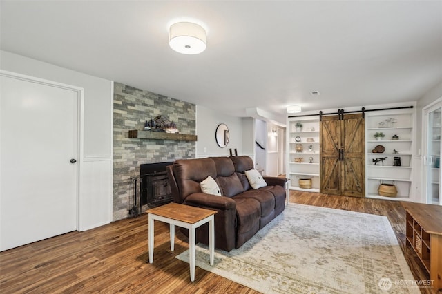 living area with a barn door, stairway, wood finished floors, and a fireplace