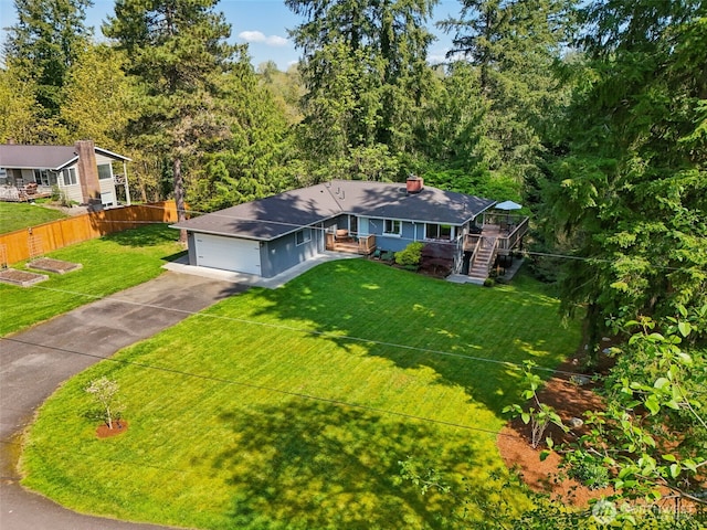 view of front of home with a front yard, a garage, driveway, a chimney, and fence
