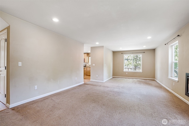 empty room featuring light carpet, recessed lighting, and baseboards