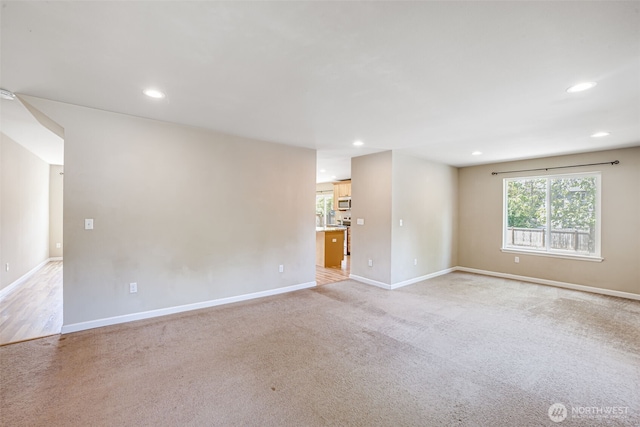 empty room featuring baseboards, recessed lighting, and light carpet
