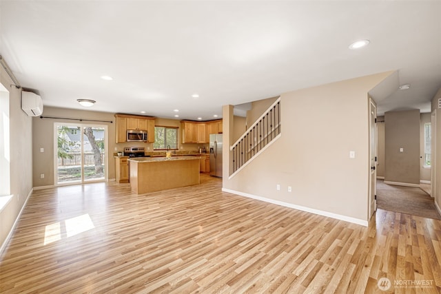 unfurnished living room with a wall unit AC, baseboards, light wood-style flooring, recessed lighting, and stairway