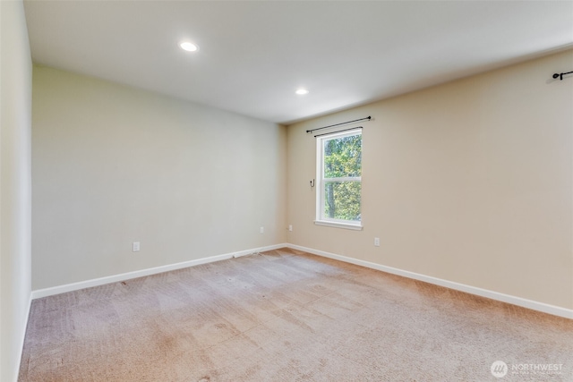 spare room featuring recessed lighting, light carpet, and baseboards