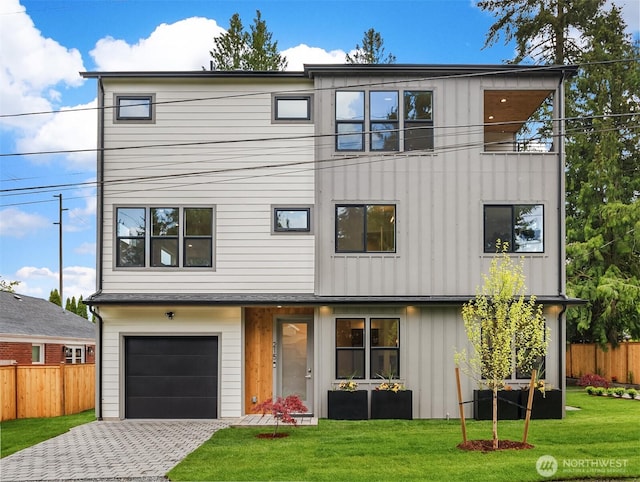 view of front of house with board and batten siding, fence, a front lawn, and a garage