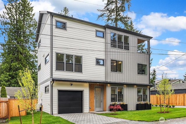 view of front of property with a garage, a front lawn, board and batten siding, and fence