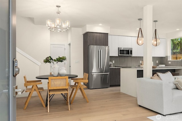 kitchen with white cabinets, appliances with stainless steel finishes, light wood finished floors, decorative backsplash, and modern cabinets