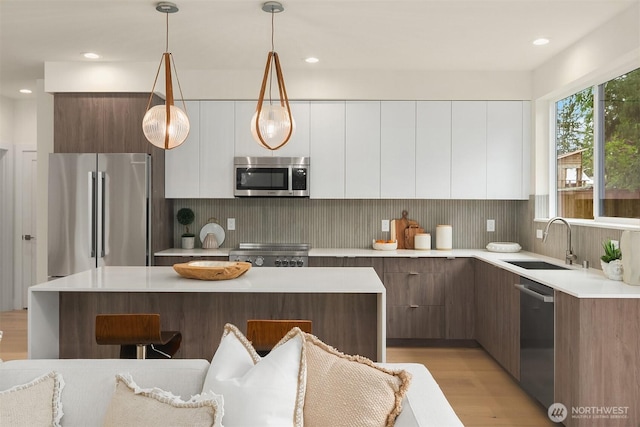 kitchen featuring light wood-style floors, a sink, modern cabinets, and stainless steel appliances