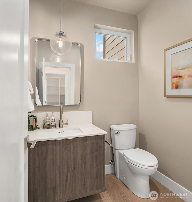 half bath with vanity, baseboards, and toilet