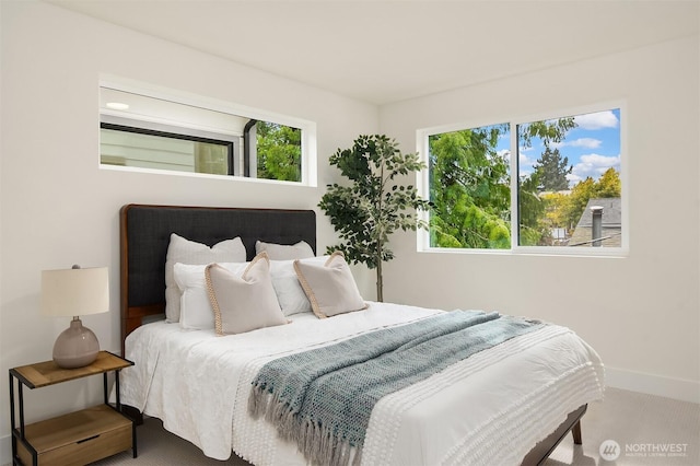 carpeted bedroom featuring baseboards and multiple windows