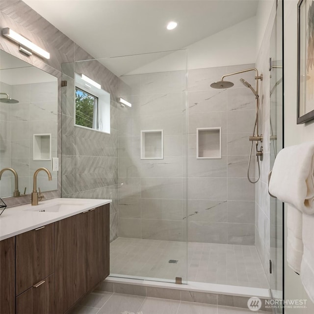 bathroom with tile patterned floors, a shower stall, lofted ceiling, and vanity