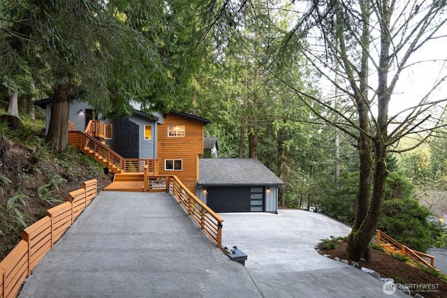 view of home's exterior featuring an attached garage, stairway, and driveway