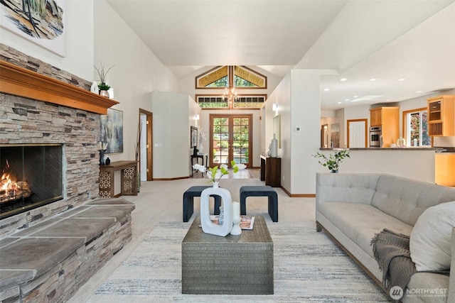 living room featuring lofted ceiling, light colored carpet, baseboards, french doors, and a stone fireplace