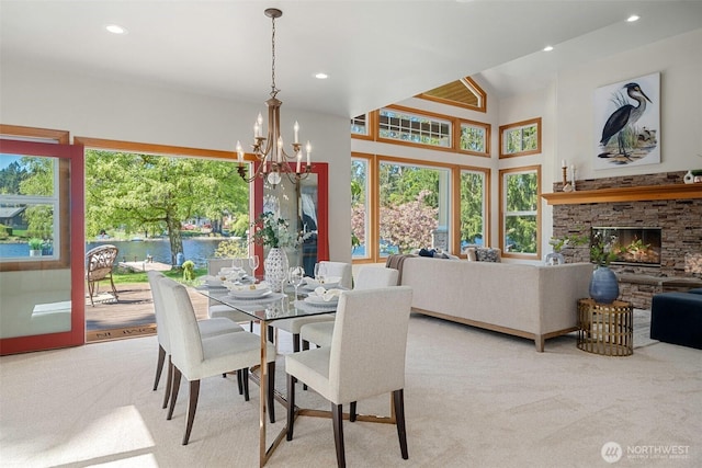 carpeted dining room with recessed lighting, a notable chandelier, a water view, and a fireplace