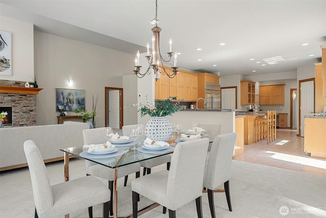 dining room featuring recessed lighting, light colored carpet, light tile patterned floors, a stone fireplace, and a notable chandelier