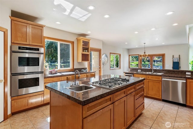 kitchen featuring light tile patterned floors, stainless steel appliances, an island with sink, and a sink