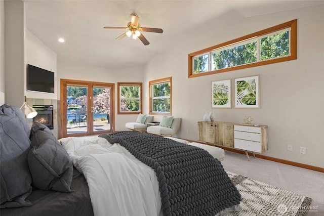 carpeted bedroom featuring a tiled fireplace, multiple windows, vaulted ceiling, and baseboards