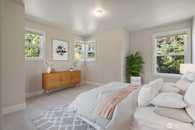 bedroom featuring light carpet and baseboards