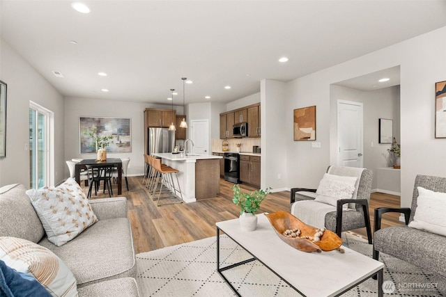 living area featuring light wood-style floors, baseboards, and recessed lighting