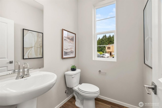 bathroom featuring a sink, baseboards, toilet, and wood finished floors