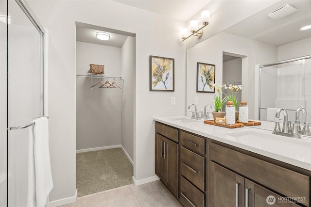 full bath with double vanity, baseboards, a sink, and a stall shower