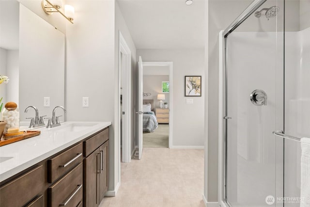 full bath with double vanity, a shower stall, a sink, baseboards, and ensuite bathroom