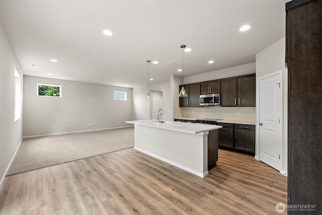 19504 15th Ave E, Spanaway, WA 98387 - kitchen featuring stainless steel microwave, dark brown cabinets, light wood-style flooring, light countertops, and recessed lighting