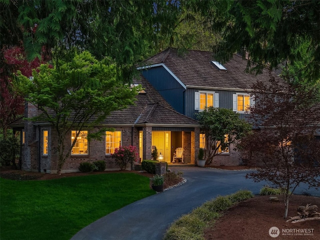 traditional-style house with brick siding, driveway, and a front lawn
