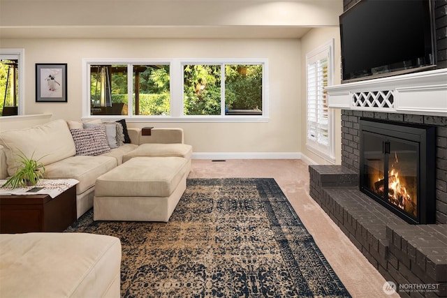 living room featuring a brick fireplace, baseboards, carpet floors, and a wealth of natural light