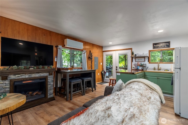 105 Robinwood Pl, Packwood, WA 98361 - living area with french doors, a wall unit AC, light wood-type flooring, wood walls, and a fireplace