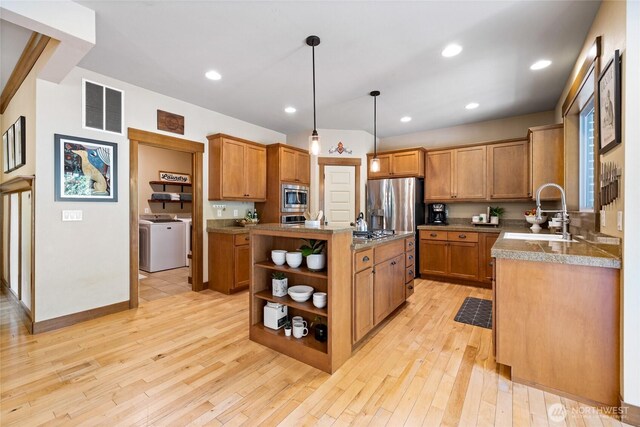 kitchen featuring visible vents, open shelves, a sink, stainless steel microwave, and washer and dryer